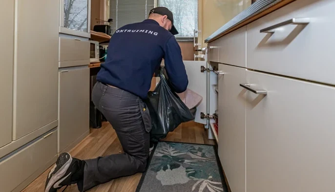 Een man is een huis aan het ontruimen met een vuilniszak